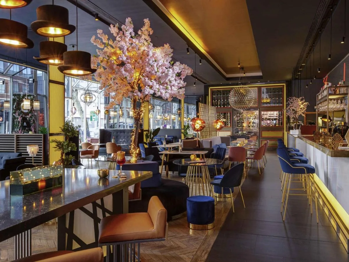 a restaurant with tables and chairs and chandeliers at Pullman London St Pancras in London