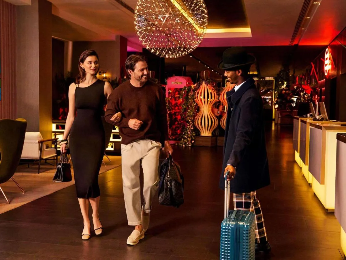 two men and a woman walking through a store with luggage at Pullman London St Pancras in London